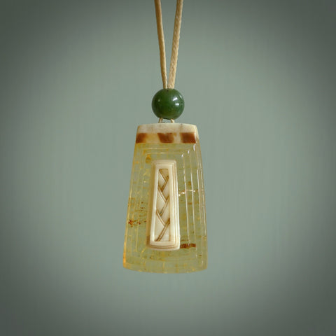 This pendant is handcrafted from rare Kauri Gum Amber with Woolly Mammoth Tusk insert. It is supplied with an adjustable tan cord. It is a graceful and very interesting piece that will attract admiration and comment. Hand carved here in New Zealand by Sami.