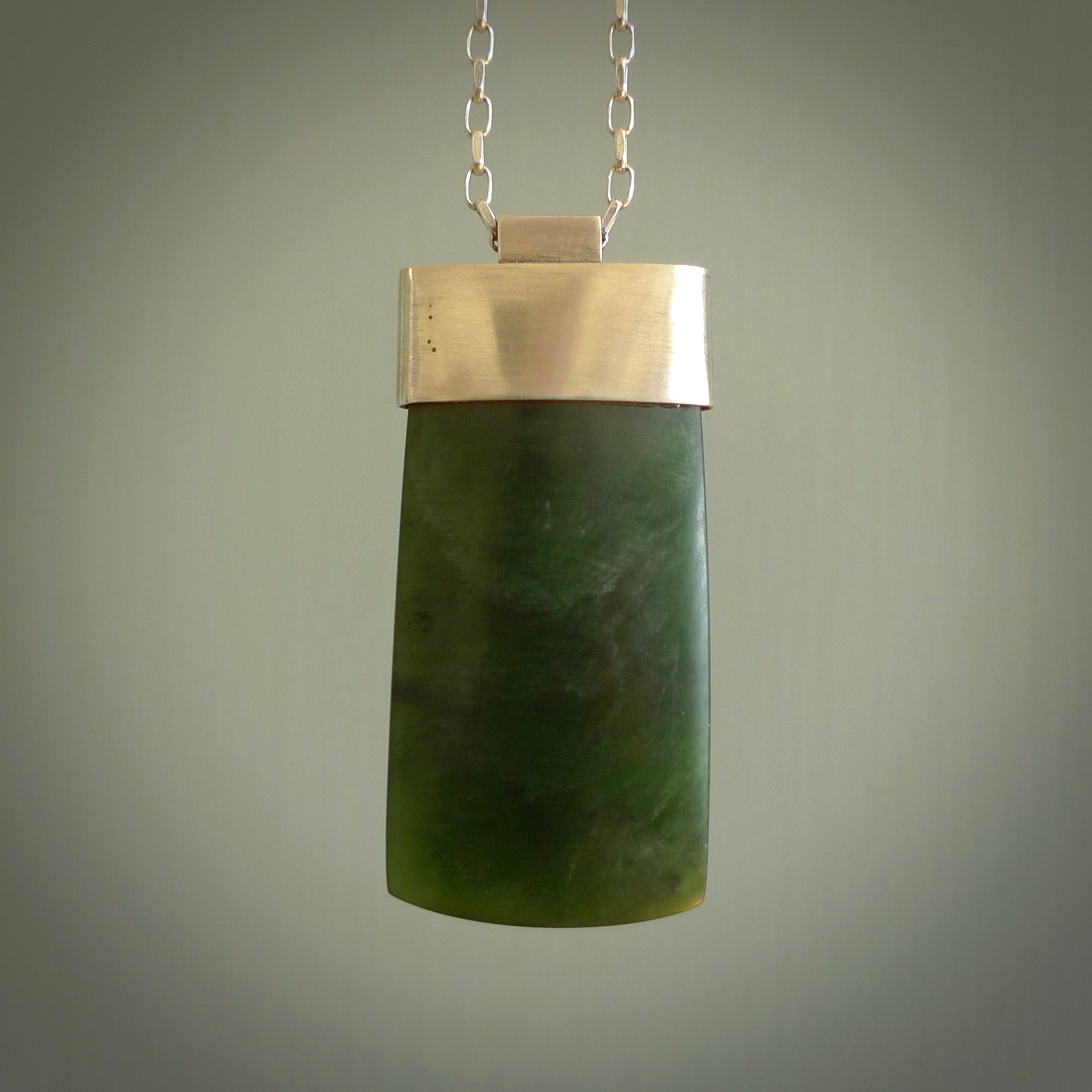 This picture shows a hand carved jade toki, drop pendant with sterling silver cap and chain. The jade is a very dark green with a shimmer in the stone. It is suspended from a sterling silver clasp and we supply a sterling silver chain. Delivery is free worldwide.