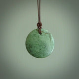 A lovely disc design with cupping on one side and the lightly convex form on the other - a little feature that captures the light and gives the piece a sense of movement and form. Hand made from New Zealand Jade by Ric Moor. Delivered with an adjustable brown cord. 