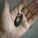 This picture shows a jade hook pendant, also called a hei-matau, carved for us in New Zealand jade. The jade is a wonderful deep mint green pounamu. This is a rare jade loved and valued for its distinctive colour. The carver is Ric Moor - and this is a beautiful example of his work. The cord is a four-plait, adjustable beige coloured necklace.