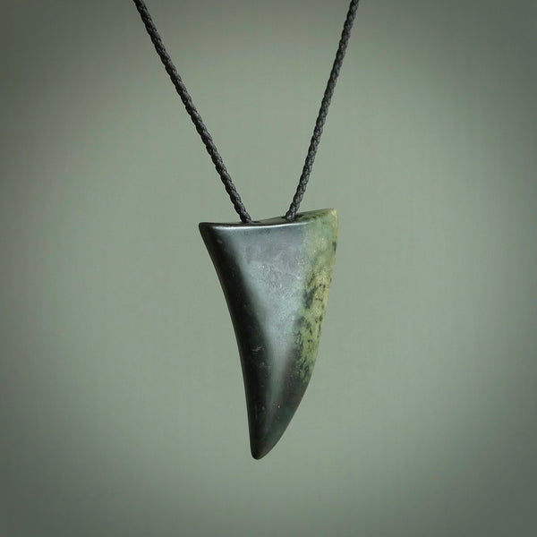 This is a lovely New Zealand Jade, pounamu drop pendant. Hand carved for us by Ric Moor. It is bound with an adjustable Black coloured cord which is length adjustable. Free worldwide shipping. The light reveals the internal structure and colour of the stone beautifully.