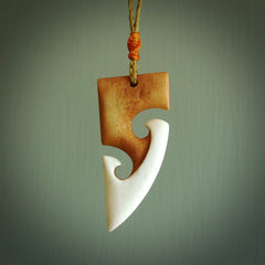A hand carved bone toki with double koru, intricate pendant. The cord is a tan colour and is adjustable. A medium sized hand made toki with koru necklace by New Zealand artist Tonijae Brockway. Tonijae has stained parts of the bone which really add to the dimension of this pendant. One off work of art to wear.