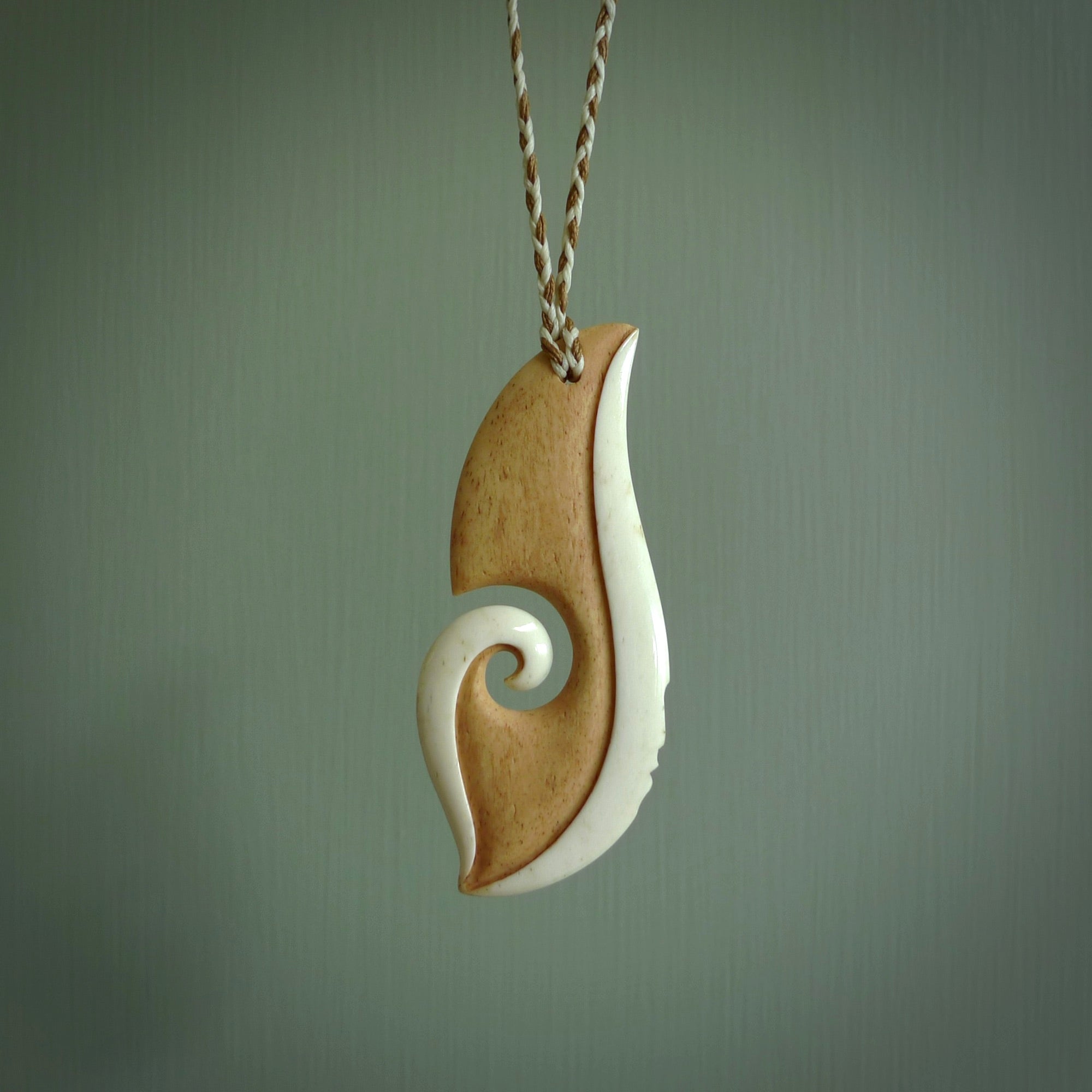 A hand carved bone contemporary, intricate pendant. The cord is a 4 strand, 3 plait in Ice White and Tan and is an adjustable length. A large sized hand made contemporary necklace by New Zealand artist Kerry Thompson. Kerry has stained parts of the bone which really add to the dimension of this pendant. One of work of art to wear.