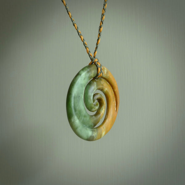A hand carved koru pendant from New Zealand Jade. The cord is a sage green and harvest gold colour and is length adjustable. A large hand made double Koru necklace by New Zealand artist Kerry Thompson.