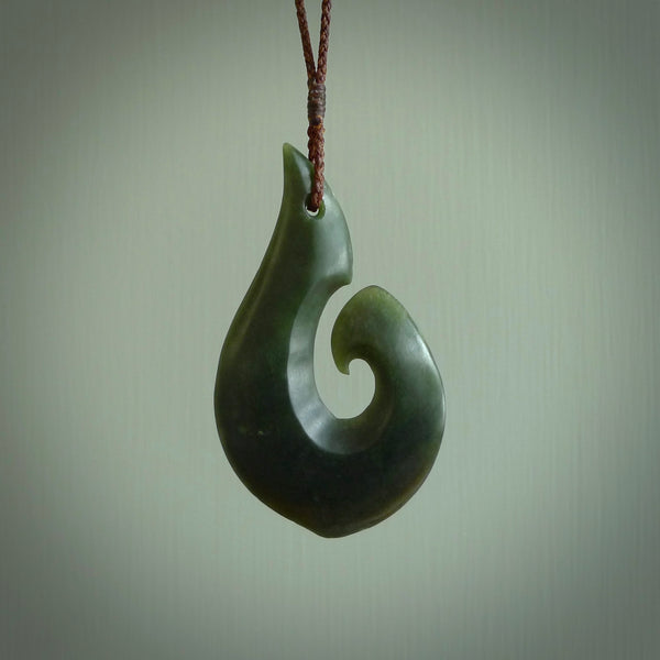 This matau, is carved from a very striking New Zealand jade. It is both intricate and simple in design - it has hidden folds and smooth curves. A piece to be worn or displayed - the carving and the jade are both magnificent. Hand carved New Zealand Jade Hook by master carver Ric Moor.
