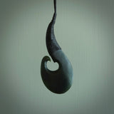 This picture shows a large deep green large jade hook pendant, also called a hei-matau, carved for us in New Zealand jade. The carver is Donna Summers - and this is a beautiful example of his work. The cord is a four-plait, adjustable black coloured necklace. 