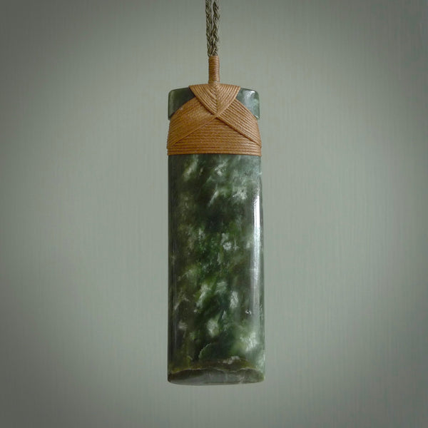A large and beautiful hand carved toki pendant. This piece is carved from New Zealand jade by NZ Pacific. This is a wonderful large toki bound with a four-plaited khaki green cord and a Gingernut Brown lashing. A beautiful, traditional toki for sale online.