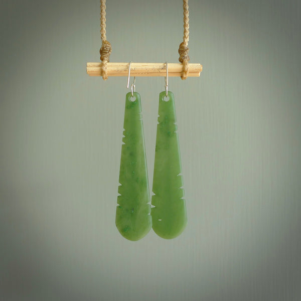 This picture shows New Zealand Pounamu, jade feather earrings with sterling silver hooks. Hand made unique and contemporary feather earrings by Kerry Thompson. Hand carved here in New Zealand from New Zealand Jade. One pair only.