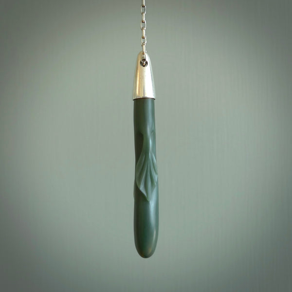 This picture shows a hand carved Inanga Pounamu, jade drop pendant with sterling silver cap and chain. The jade is a very dark green with a shimmer of light blue tones in the stone. It is suspended from a sterling silver clasp and we supply a sterling silver chain. Delivery is free worldwide.