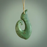 This picture shows a hand carved jade koru pendant. It is a deep green colour and is a wonderful, large sized piece of jewellery. The cord is a four plait beige colour and adjustable so that you can position the pendant where it suits you best. This koru was carved for us by Ric Moor. Delivery is free worldwide.