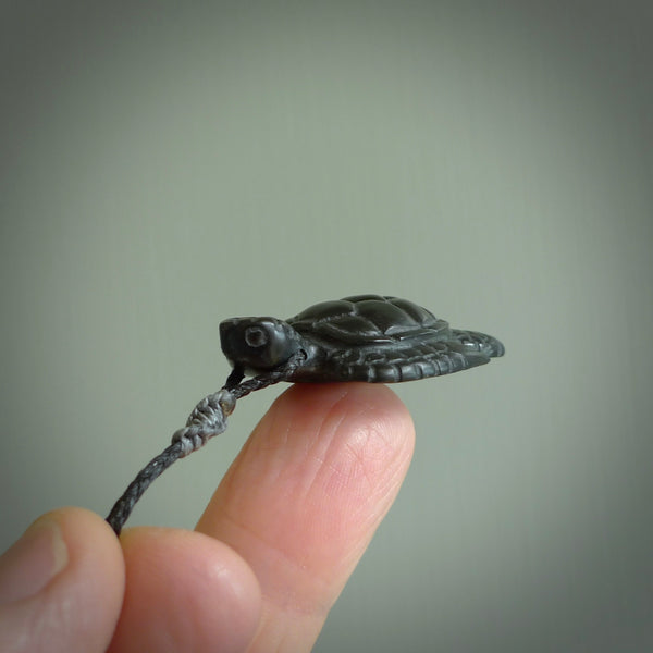 This picture shows a hand carved black jade turtle pendant. It is polished to a soft shine and has quite a lot of detail carved into the jade. The cord is a hand plaited black, waxed polyester. Carved by NZ Pacific.