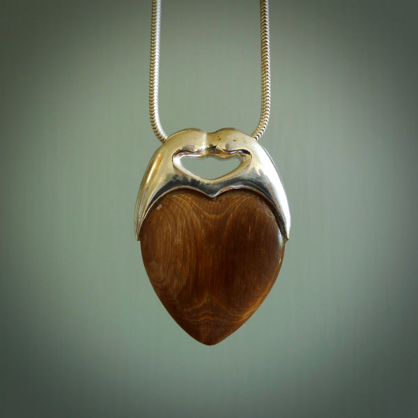 This picture shows a pendant that we have carved in a combination of sterling silver and woolly mammoth. It shows a symbolic kiss, with two heads coming together and both embracing a woolly mammoth heart. The necklace is a sterling silver chain.