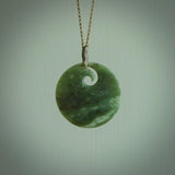 This is a large green New Zealand jade koru pendant. We have bound this with a fine khaki coloured cord necklace. The necklace is adjustable so you can position the piece where it suits you the best. Hand made by Ric Moor.