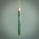 This picture shows a hand carved Inanga Pounamu, jade drop pendant with sterling silver cap and chain. The jade is a very dark green with a shimmer of light blue tones in the stone. It is suspended from a sterling silver clasp and we supply a sterling silver chain. Delivery is free worldwide.