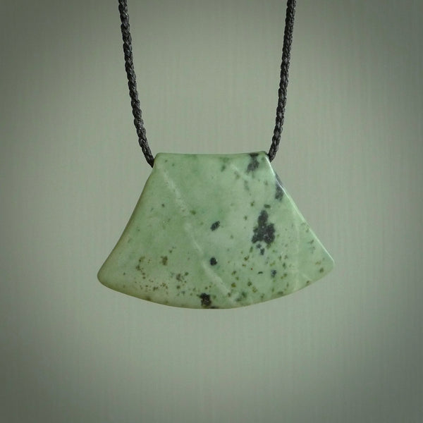 This picture shows a hand carved jade contemporary half-shield pendant. It is a mint green colour. This is a wonderful piece of jewellery. The cord is hand plaited and adjustable so that you can position the pendant where it suits you best. This piece was carved for us by Ric Moor. Delivery is free worldwide.