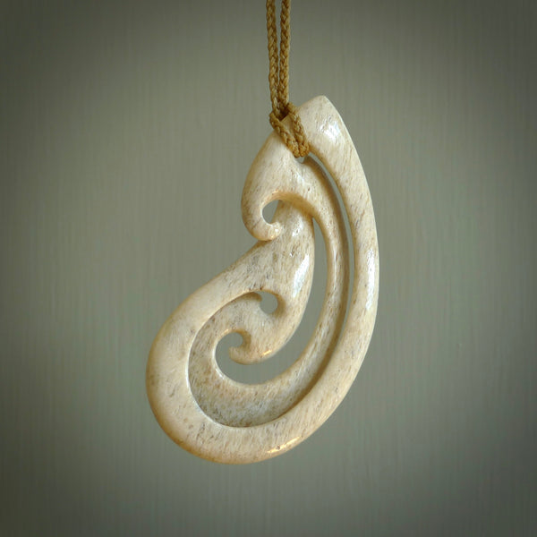 A hand carved intricate and complex hook design pendant from Whale Bone. The cord is tan and adjustable in length. Large hand made woven necklace by New Zealand artist Kerry Thompson.