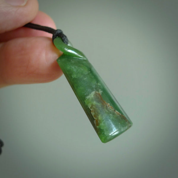 This pendant is a flower jade single twist. It is handcarved from New Zealand flower jade and has a mix of green, mint and pale gold colours interspersed throughout the stone. It has a fine twist, small and light. The cord is hand plaited and can be adjusted. The cord colour on this piece is Khaki. Two sizes available.