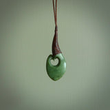 This picture shows a large deep green large jade hook pendant, also called a hei-matau, carved for us in New Zealand jade. The carver is Donna Summers - and this is a beautiful example of his work. The cord is a four-plait, adjustable brown coloured necklace.