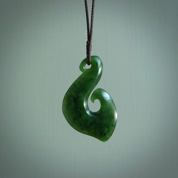 This picture shows a jade hook pendant, also called a hei-matau, carved for us in New Zealand jade. The carver is Ric Moor - and this is a beautiful example of his work. The cord is a four-plait, adjustable brown coloured necklace.