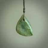 This is a lovely New Zealand Jade, pounamu drop pendant. Hand carved for us by Ric Moor. It is bound with an adjustable beige coloured cord which is length adjustable. Free worldwide shipping. The light reveals the internal structure and colour of the stone beautifully.