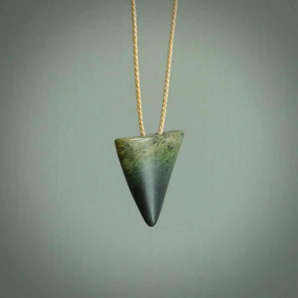 This is a lovely New Zealand Jade, pounamu drop pendant. Hand carved for us by Ric Moor. It is bound with an adjustable beige coloured cord which is length adjustable. Free worldwide shipping. The light reveals the internal structure and colour of the stone beautifully.