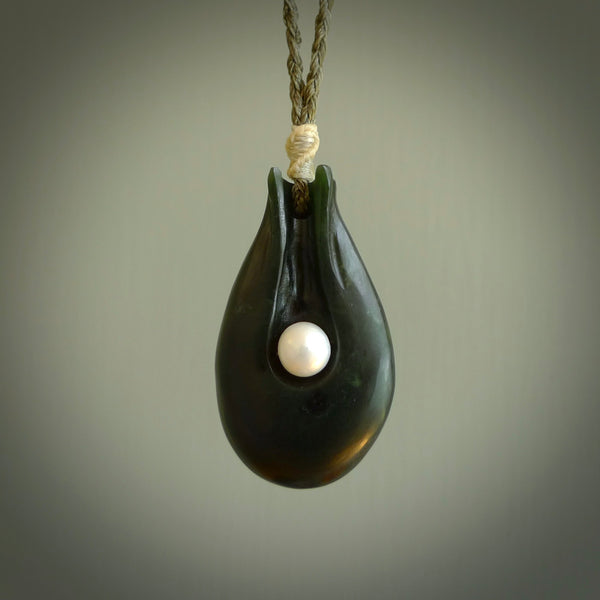 This is a unique contemporary drop pendant, hand carved from New Zealand Jade with Pearl insert. The cord is olive green and is length adjustable. This is delivered to you with Express Courier. Hand carved Pounamu, Jade necklace with adjustable cord from Ana Krakosky.