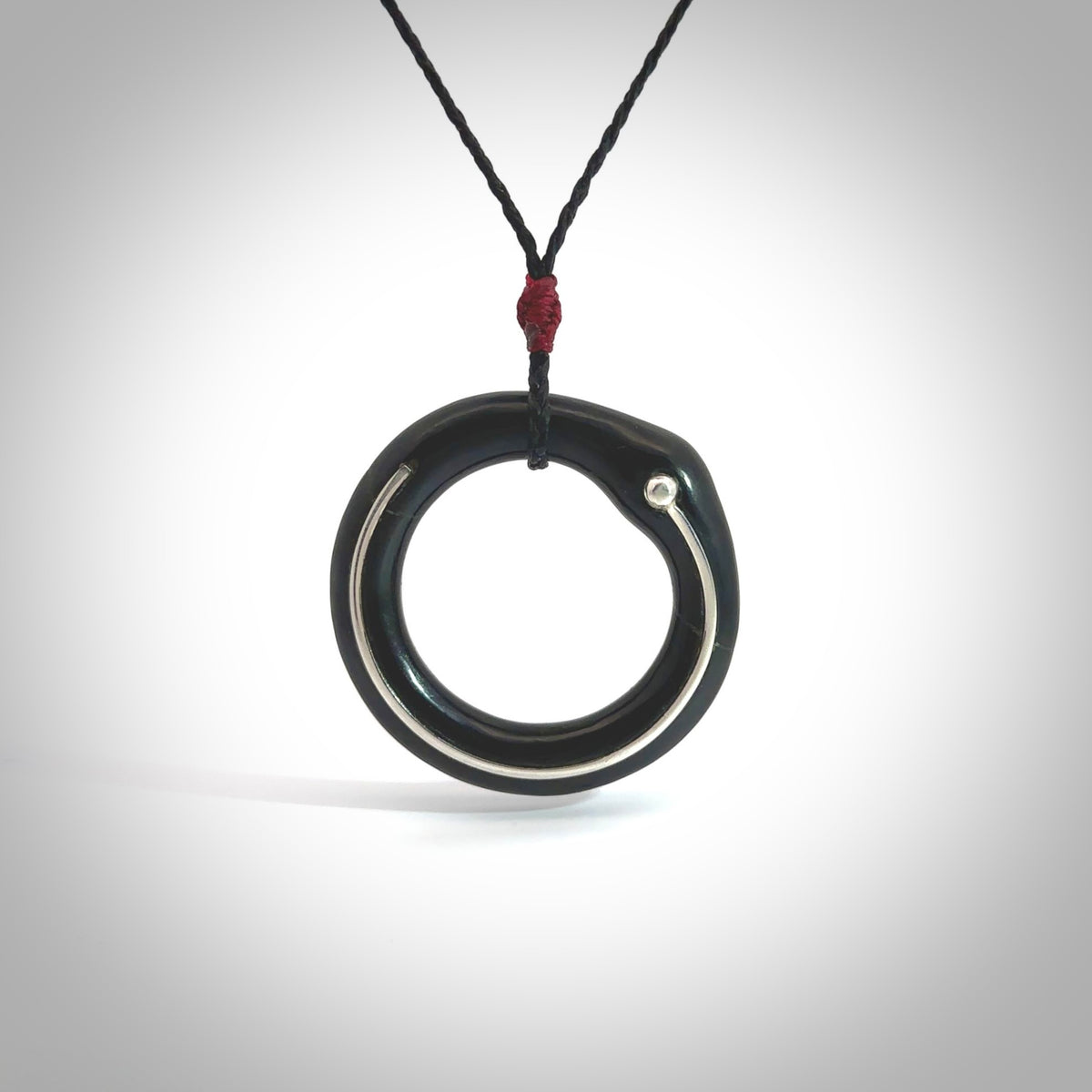 This picture shows a hand carved black jade circle pendant with sterling silver inlay. It is suspended from an adjustable Black cord. Delivery is free worldwide.