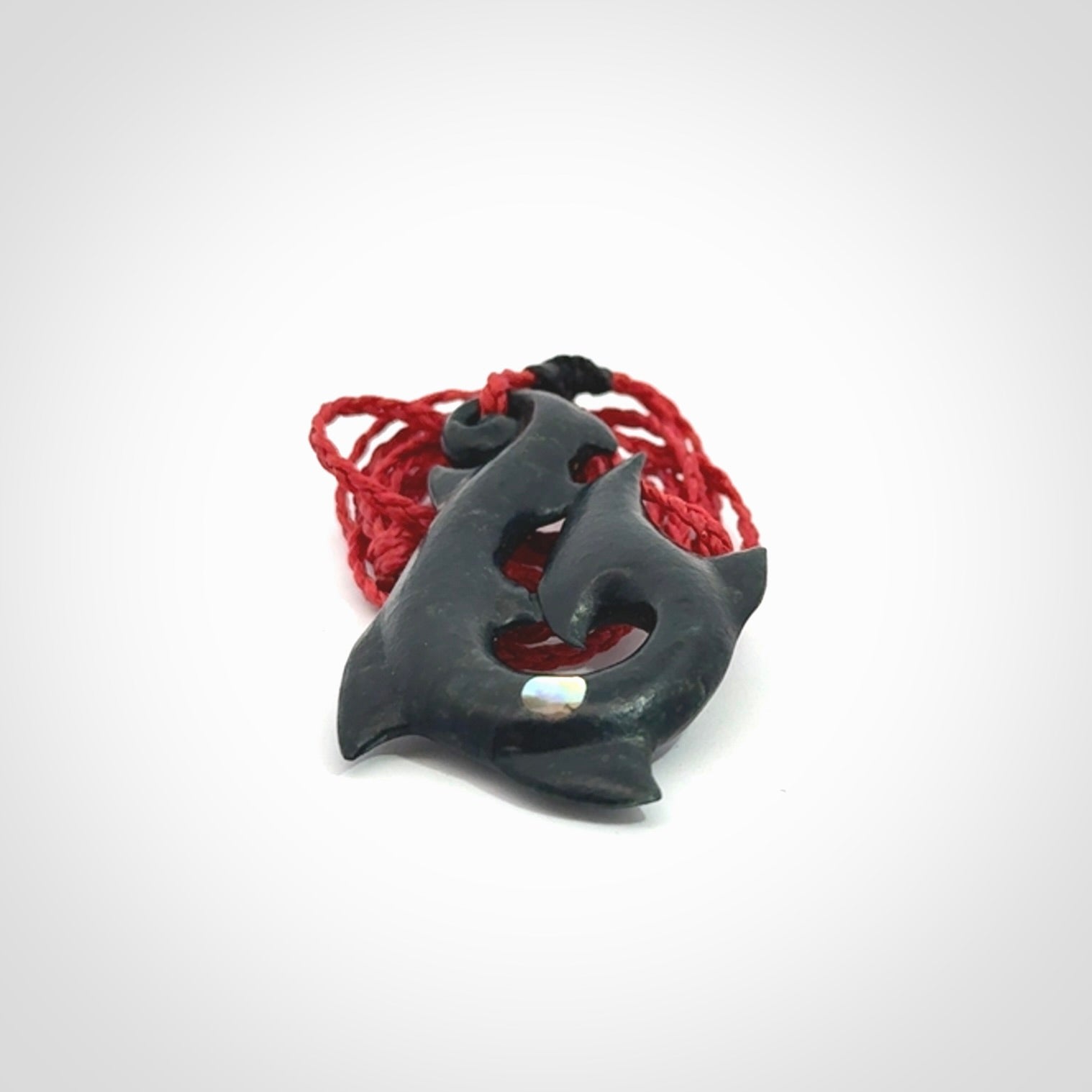 This hook, is carved from a very striking dark green piece of New Zealand jade. It has paua shell inlay and is bound with an adjustable cord.