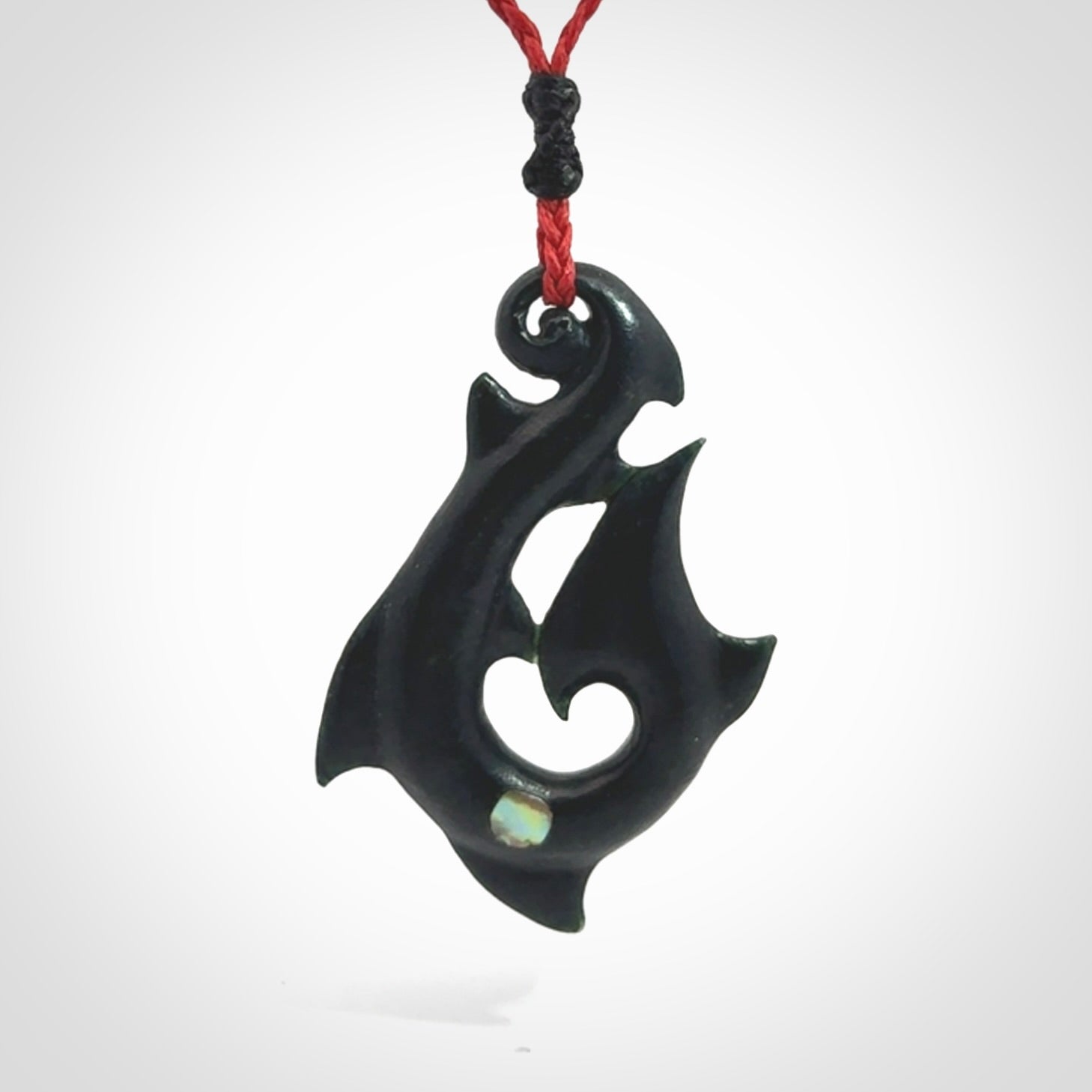This hook, is carved from a very striking dark green piece of New Zealand jade. It has paua shell inlay and is bound with an adjustable cord.