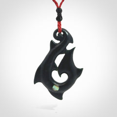 This hook, is carved from a very striking dark green piece of New Zealand jade. It has paua shell inlay and is bound with an adjustable cord.