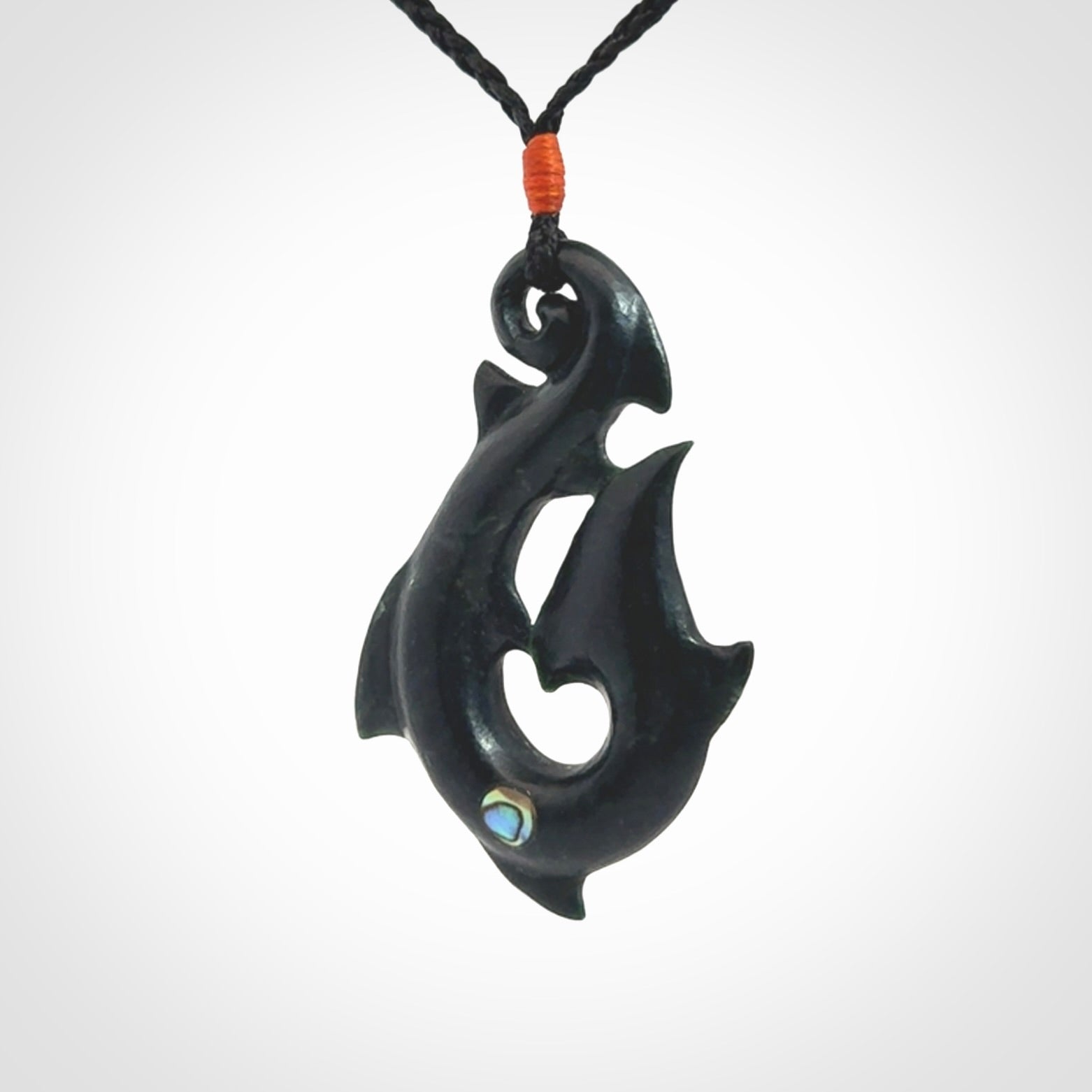 This hook, is carved from a very striking dark green piece of New Zealand jade. It has paua shell inlay and is bound with an adjustable cord.