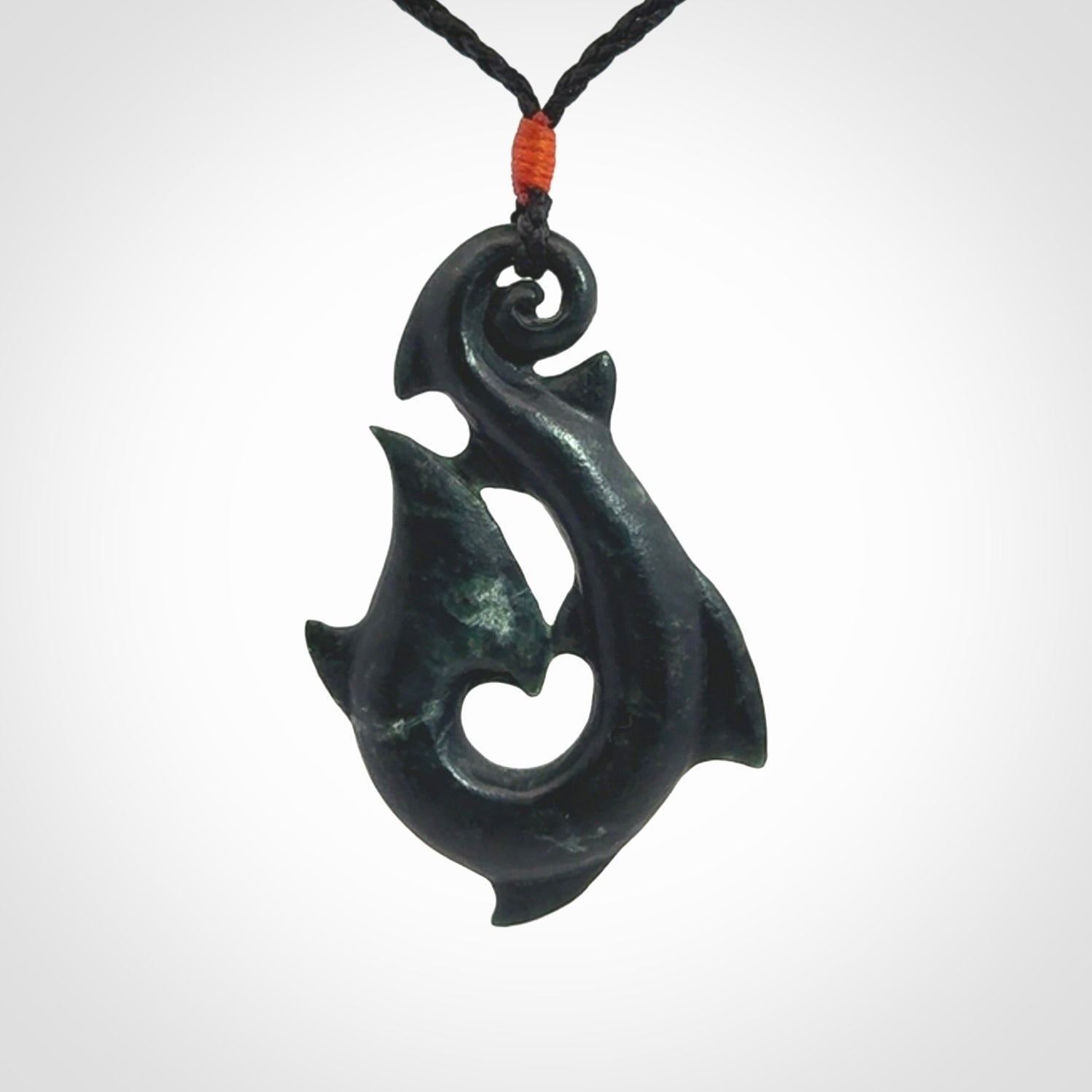 This hook, is carved from a very striking dark green piece of New Zealand jade. It has paua shell inlay and is bound with an adjustable cord.