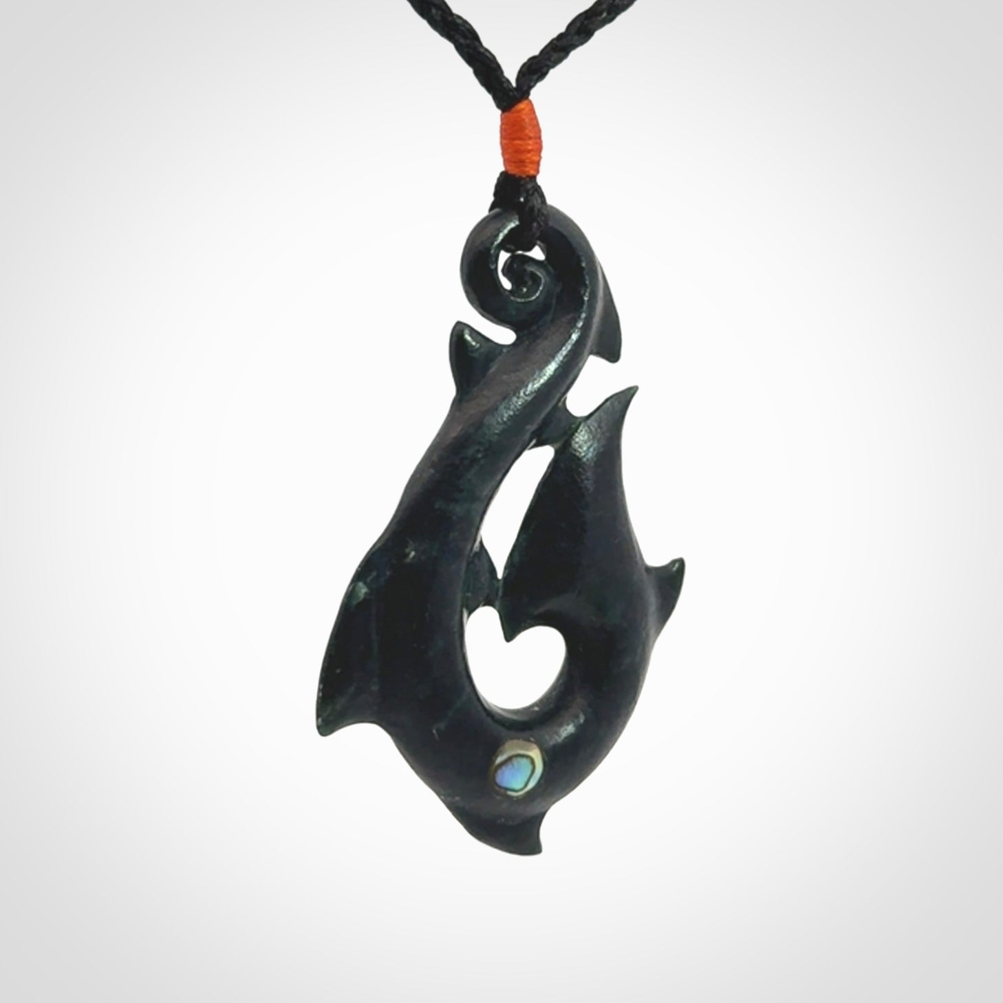 This hook, is carved from a very striking dark green piece of New Zealand jade. It has paua shell inlay and is bound with an adjustable cord.