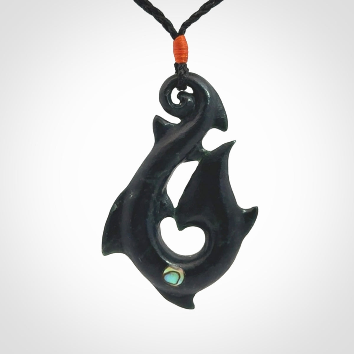 This hook, is carved from a very striking dark green piece of New Zealand jade. It has paua shell inlay and is bound with an adjustable cord.