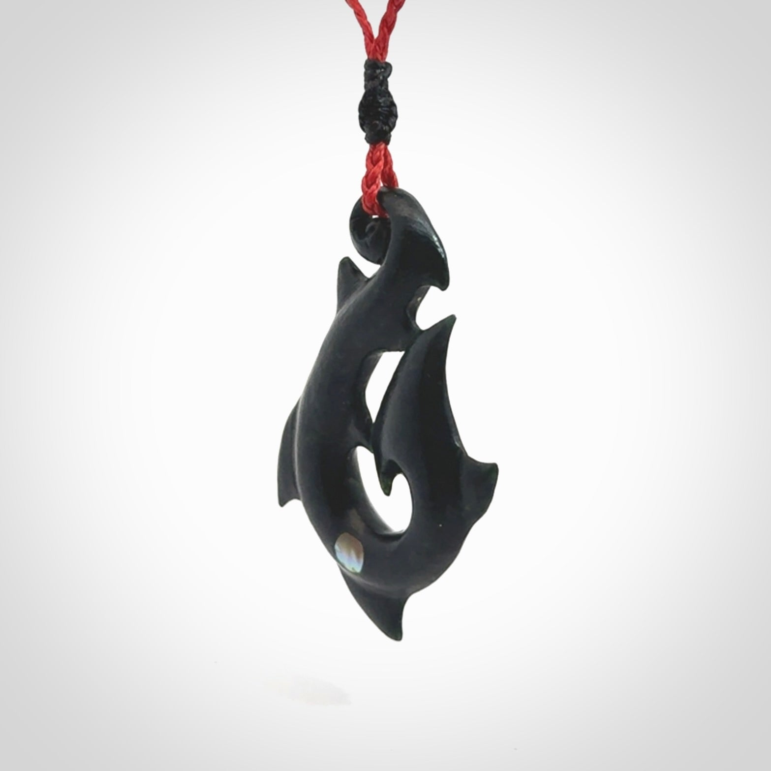 This hook, is carved from a very striking dark green piece of New Zealand jade. It has paua shell inlay and is bound with an adjustable cord.