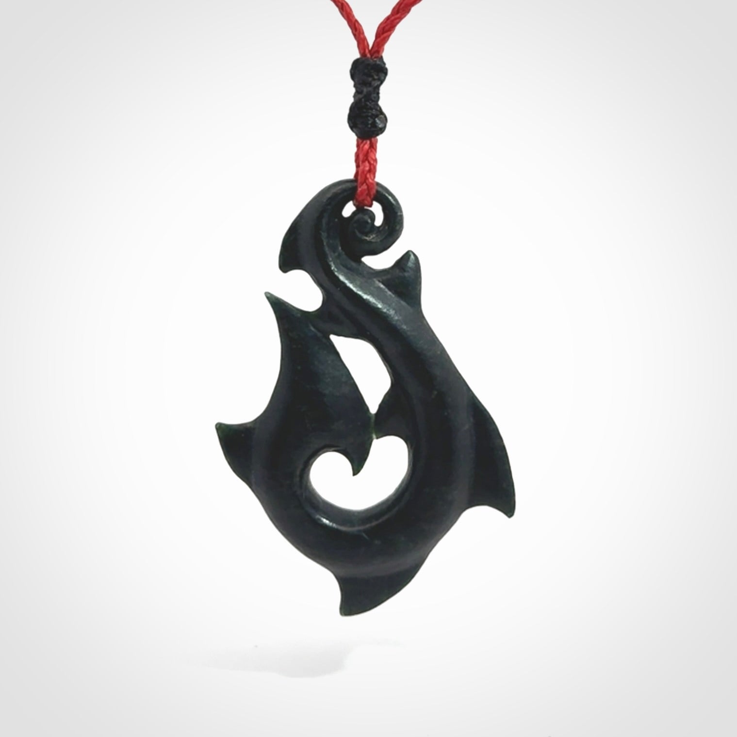 This hook, is carved from a very striking dark green piece of New Zealand jade. It has paua shell inlay and is bound with an adjustable cord.