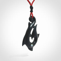 This hook, is carved from a very striking dark green piece of New Zealand jade. It has paua shell inlay and is bound with an adjustable cord.