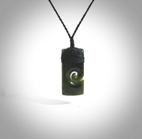 This picture shows a small toki pendant with a koru carved into the side. The cord is plaited and is length adjustable. This is a small toki pendant carved from beautiful New Zealand jade.