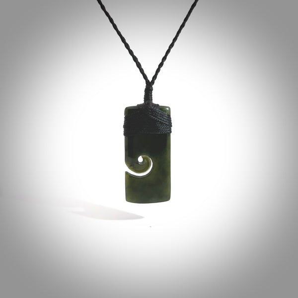 This picture shows a small toki pendant with a koru carved into the side. The cord is plaited and is length adjustable. This is a small toki pendant carved from beautiful New Zealand jade.