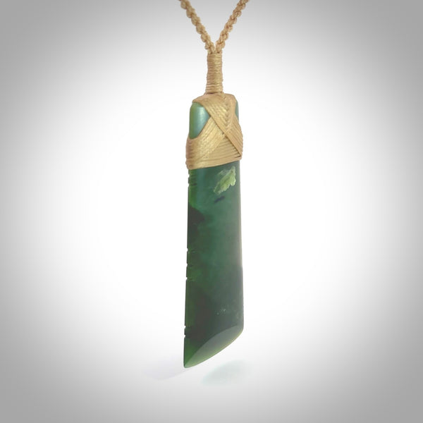 A large and beautiful hand carved toki pendant. This piece is carved from New Zealand jade by Jeromy Van Riel. This is a wonderful large toki bound with a hand-plaited cord and a traditional lashing. A beautiful, traditional toki for sale online.