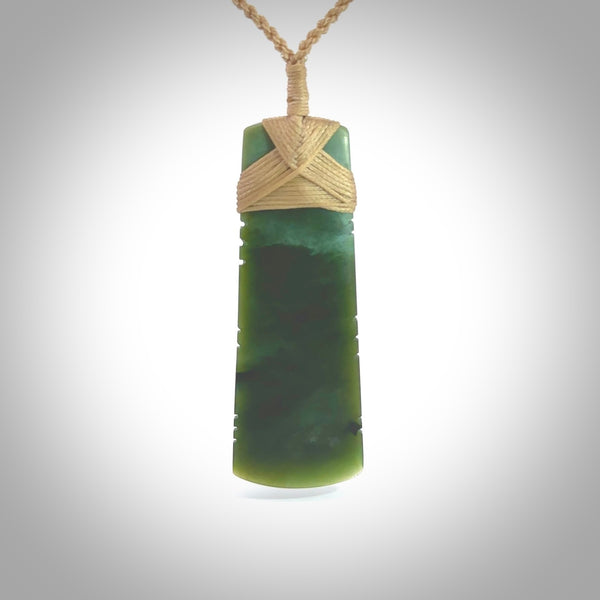 A large and beautiful hand carved toki pendant. This piece is carved from New Zealand jade by Jeromy Van Riel. This is a wonderful large toki bound with a hand-plaited cord and a traditional lashing. A beautiful, traditional toki for sale online.