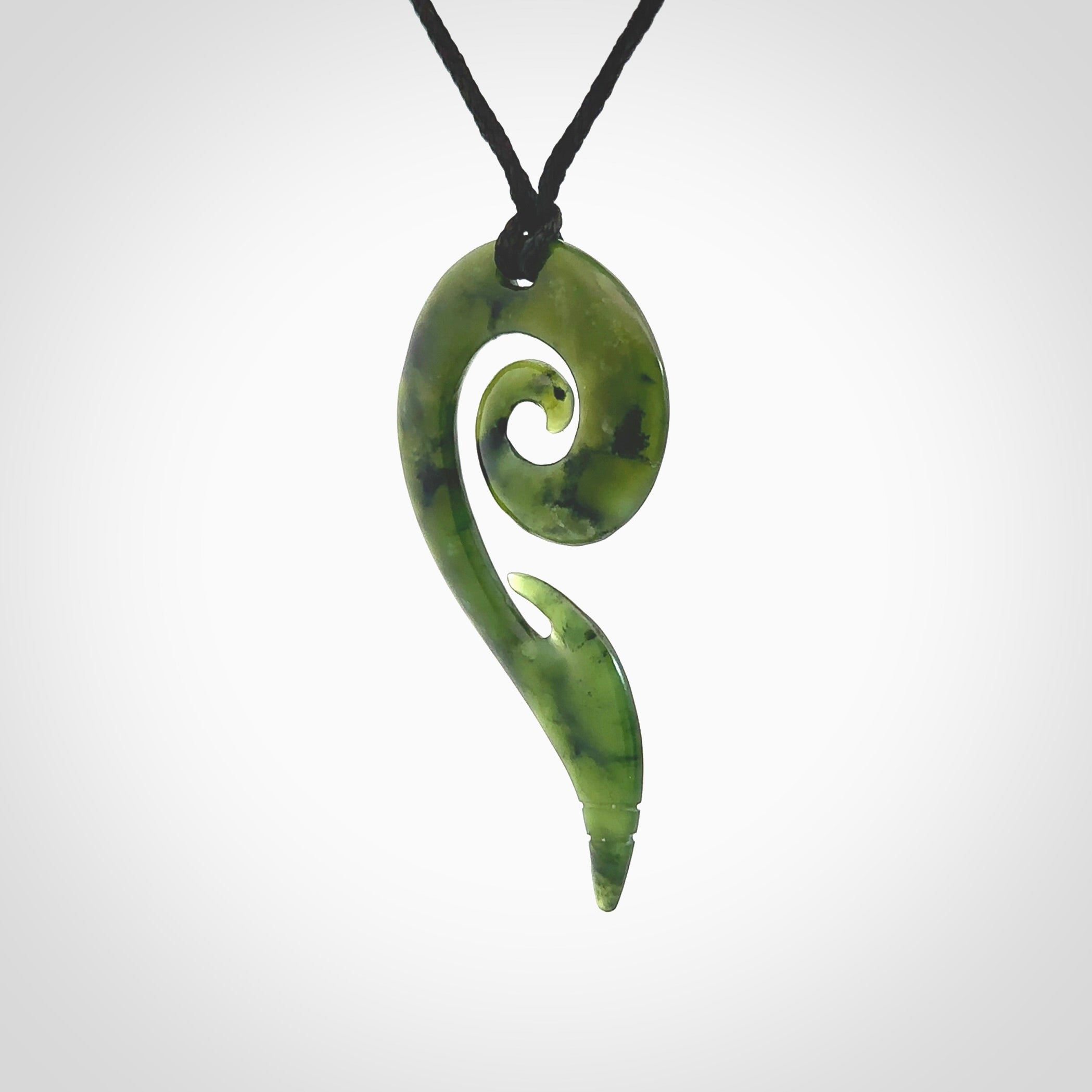 This photo shows a koru pendant carved from New Zealand Jade. The artist, Shaun Gardiner, has carved this beautifully. We provide this piece with an adjustable Black cord. This is a fantastic work of art, we have one only.