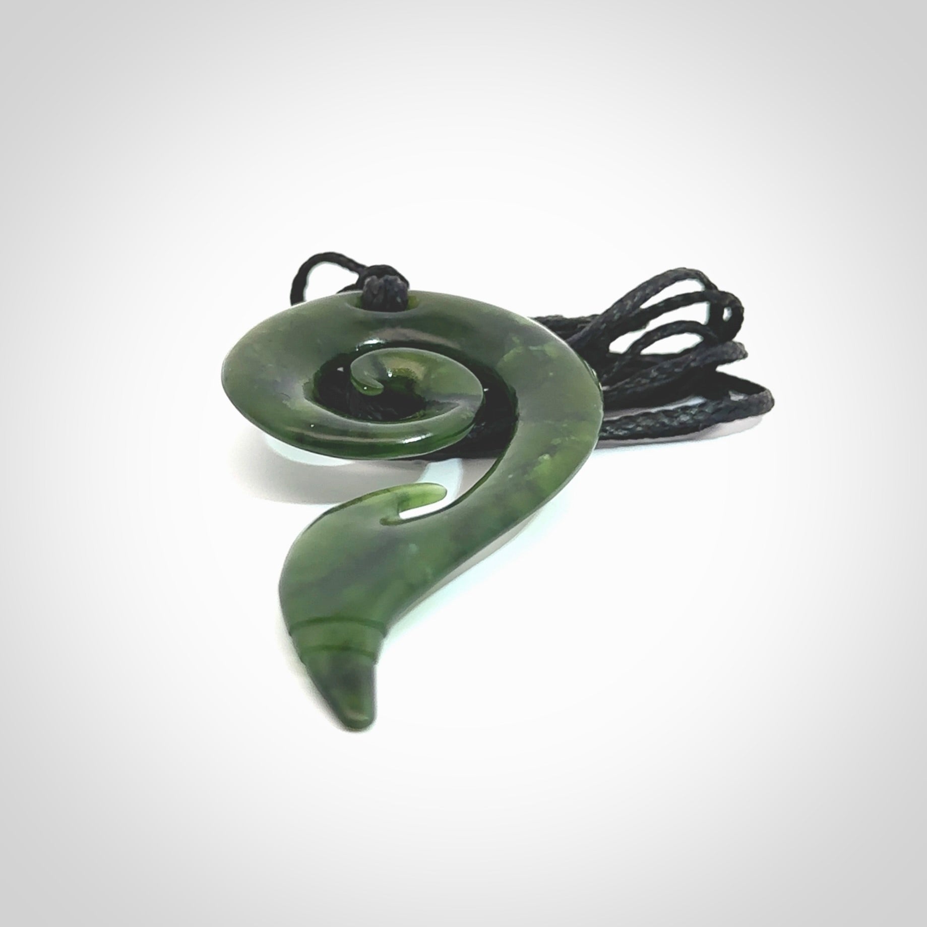 This photo shows a koru pendant carved from New Zealand Jade. The artist, Shaun Gardiner, has carved this beautifully. We provide this piece with an adjustable Black cord. This is a fantastic work of art, we have one only.