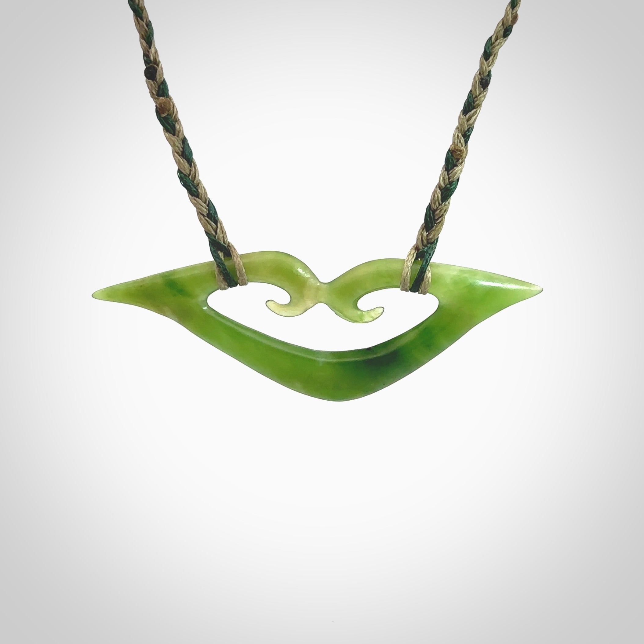 This photo shows a koru pendant carved from New Zealand Jade. The artist, Shaun Gardiner, has carved this beautifully. We provide this piece with a fixed length cord in a two toned green colour. This is a fantastic work of art, we have one only.