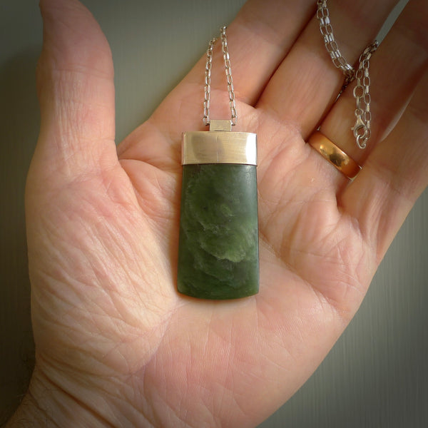 This picture shows a hand carved jade toki, drop pendant with sterling silver cap and chain. The jade is a very dark green with a shimmer in the stone. It is suspended from a sterling silver clasp and we supply a sterling silver chain. Delivery is free worldwide.
