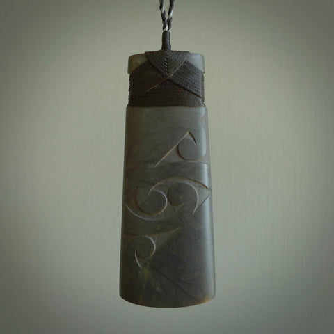 Hand carved New Zealand Argillite Toki by Rueben Tipene. We provide this large toki on an adjustable cord and ship to you in a kete pouch with Express Courier. This is a one off pendant that once sold will be removed from our site.