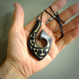 A hand carved hook design pendant, carved in New Zealand Tangiwai Jade with Gold Enamel. The colour is a beautiful dark and deep green and it is engraved on one side with a flowing design. The cord is black and is length adjustable.