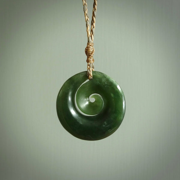 This pendant is a medium sized and gorgeous koru necklace carved from a deep green piece of New Zealand  Jade. Ross Crump carved this piece for us so the workmanship is outstanding. Handmade in New Zealand, a beautiful piece of jade jewellery.