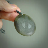Hand carved jade disc pendant. One side has a double koru etched into the face. This is a subtle and beautiful design. The other side is plain. The cord is a tan colour and is adjustable. The piece was carved for NZ Pacific by Rueben Tipene.