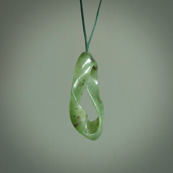 This little piece is a hand carved möbius ribbon pendant. We've carved this from Nephrite Jade from Aceh. It has very subtle colour variations in the stone and is a delightful, small and artistic piece of jewellery.
